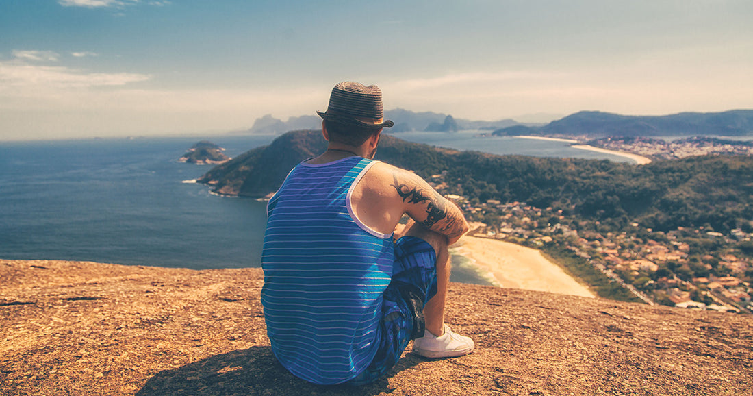 man with tattoo sitting on scenic overlook