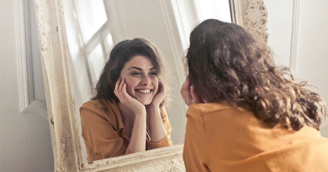 smiling woman looks at her body image in mirror
