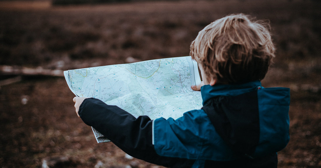 kid in blue jacket looking at map