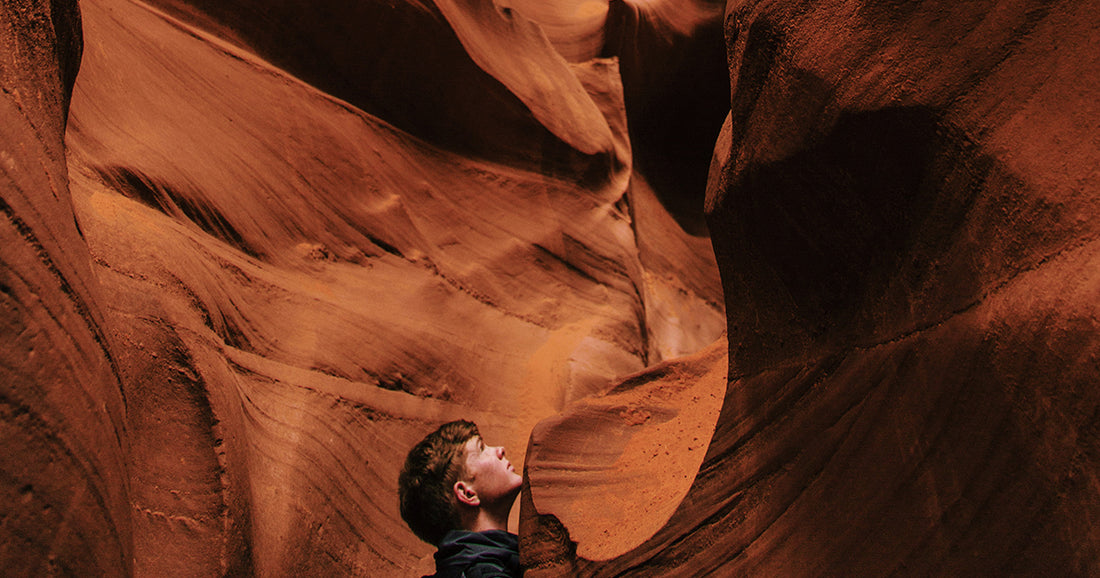 young man looks up rock wall