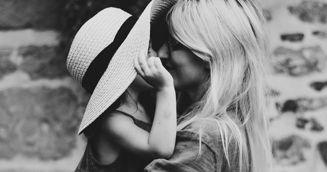 a young girl in wide-brimmed hat smiling at her mother