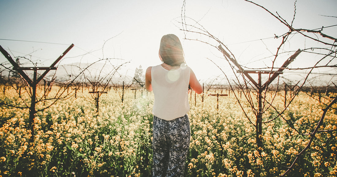 woman standing in field of flowers with withering vines