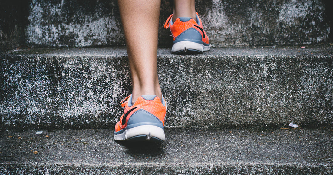 person in gray and orange shoes running up concrete steps