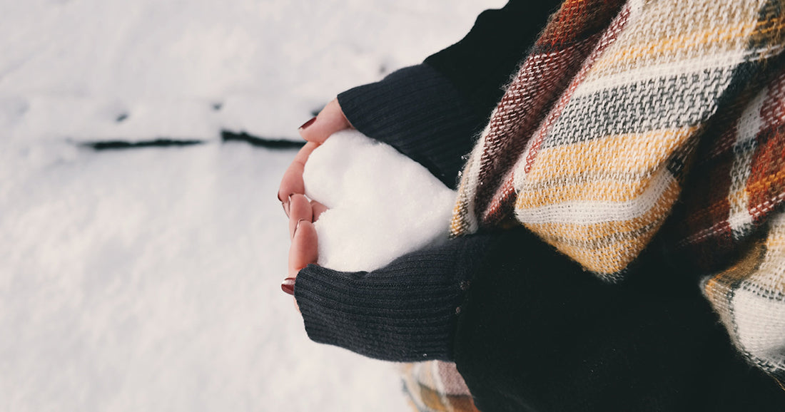 girl holding snow in the shape of a heart