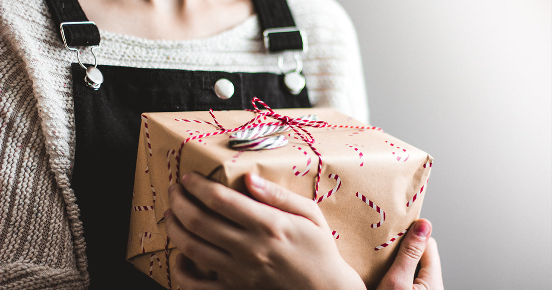 woman clutching Christmas present wrapped in brown paper with red bow