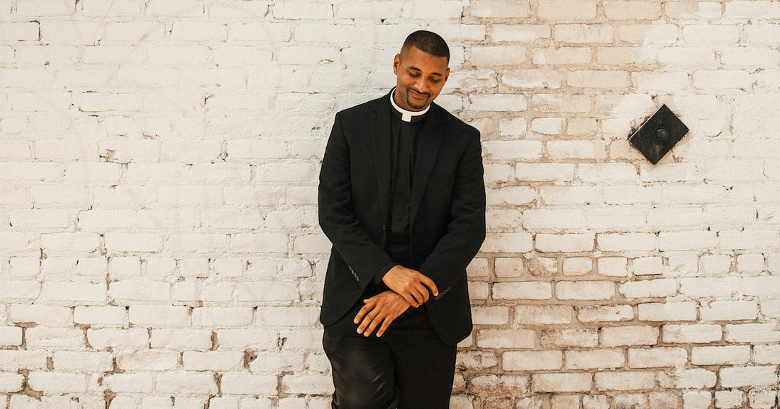 Fr. Josh in front of a white brick wall