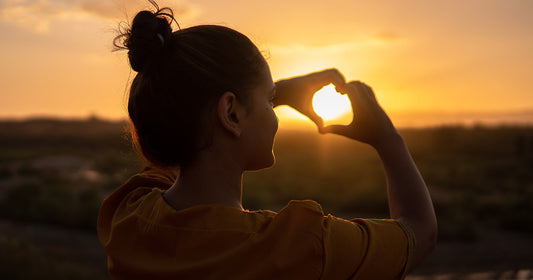 woman in yellow standing before sunset