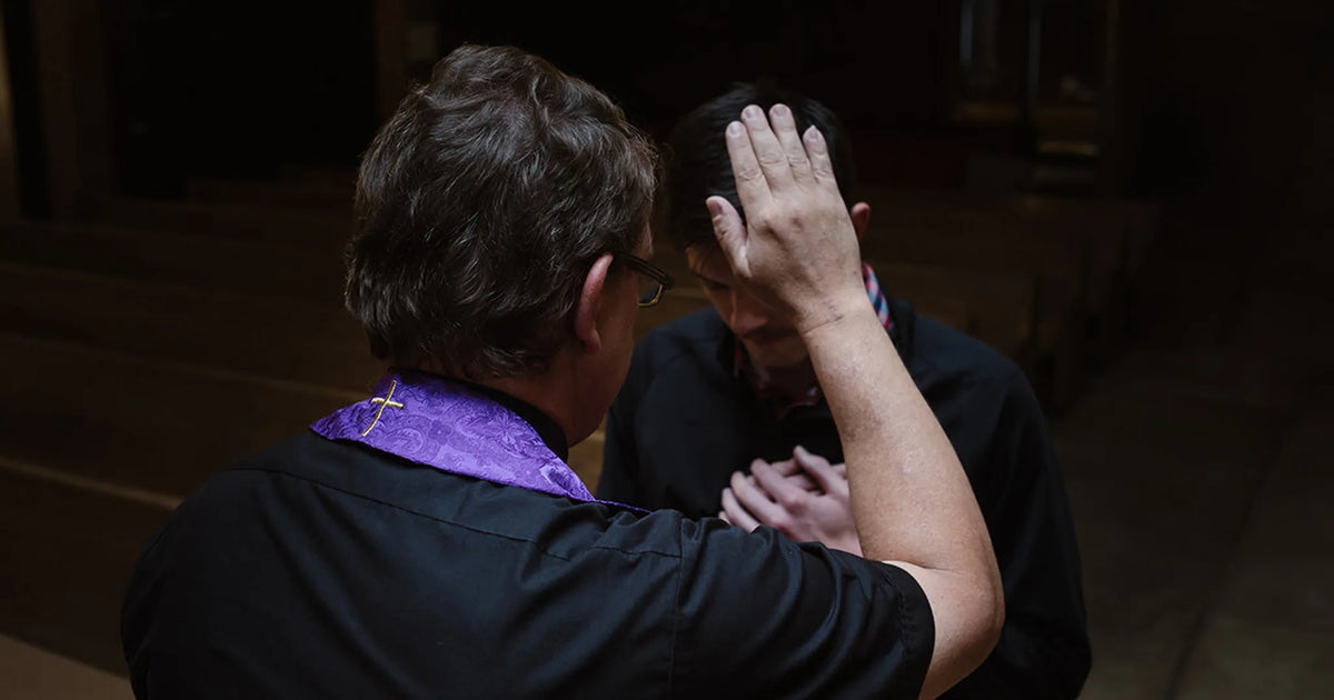 priest praying over a person during the sacrament of reconciliation