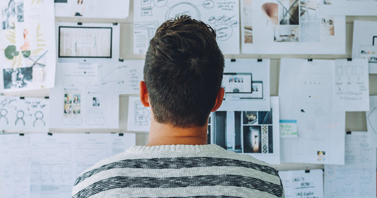 man looks at wall with different graphs and papers