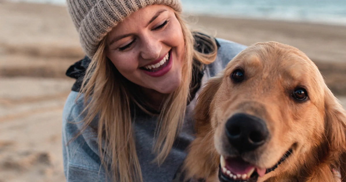 girl in hat petting dog at the beach