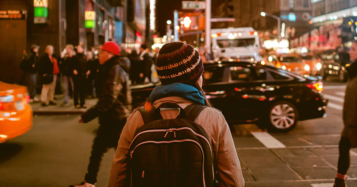 person in hat walking down city street during commute