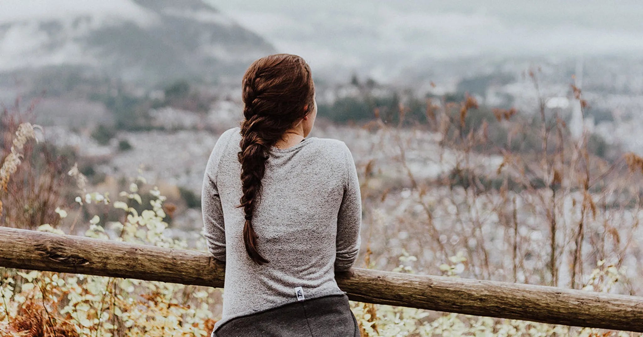 woman with braided hair standing before a mountain view