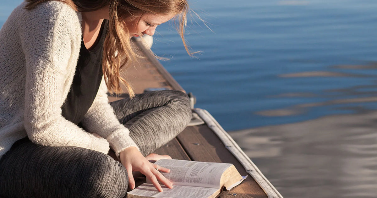 person reading bible by body of water