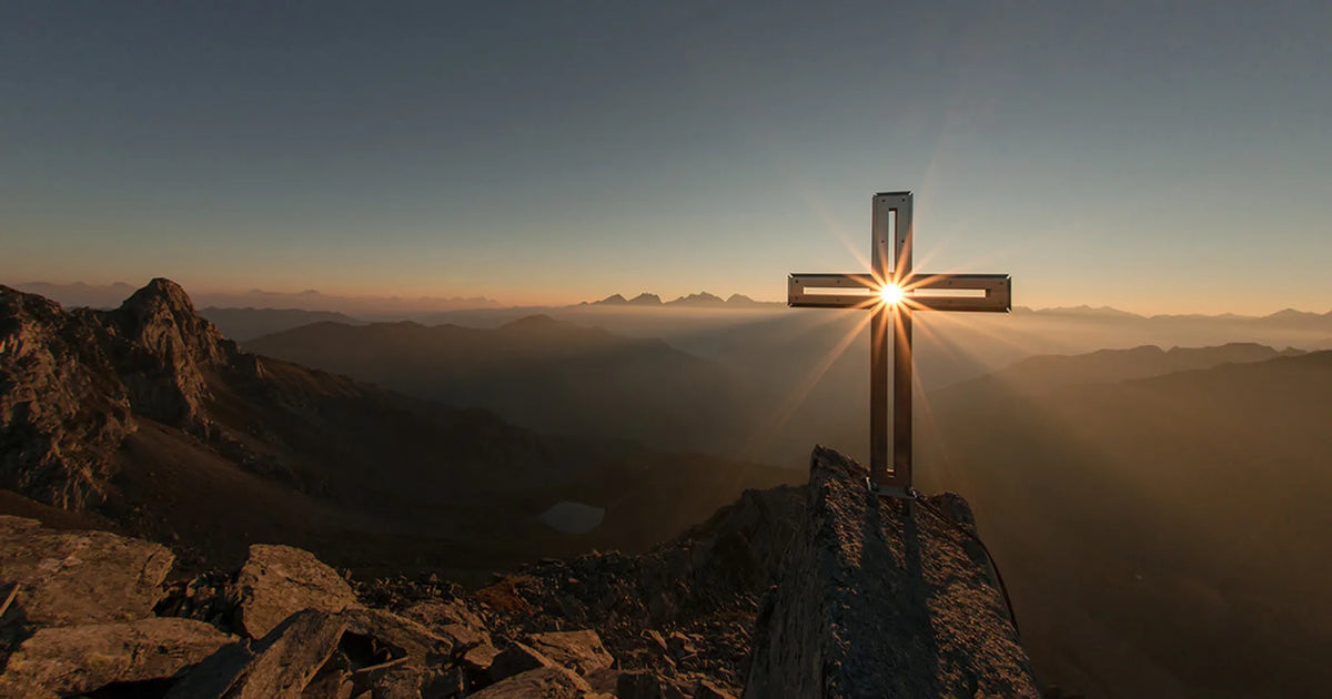 Sunlight shining through cross on mountain