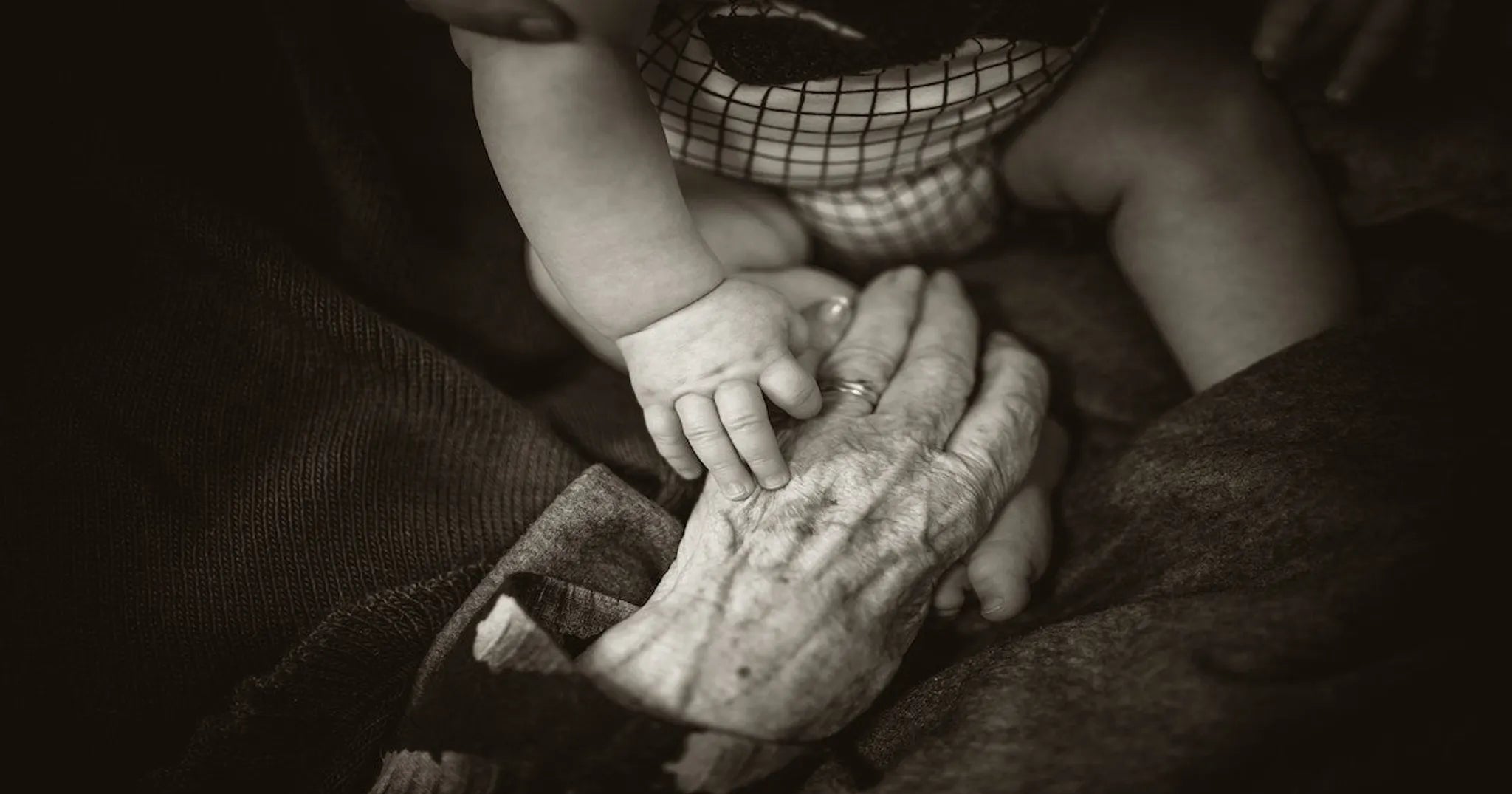 baby reaches out to hand of grandmother