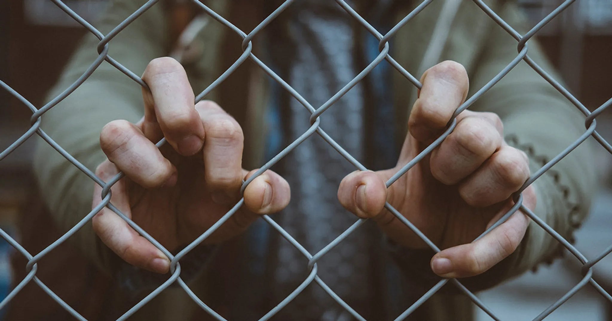 man in green jacket grips fence