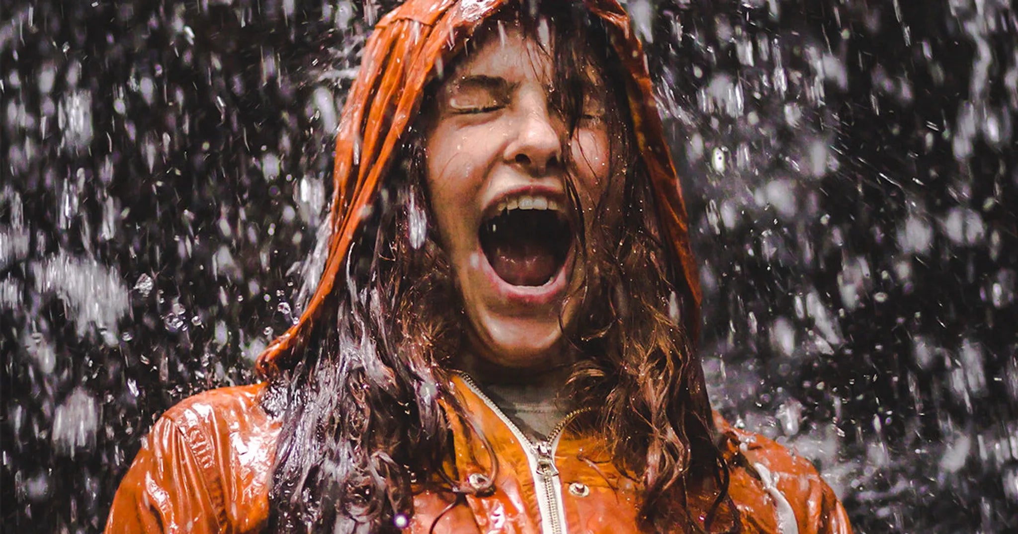woman wearing orange jacket in heavy rain