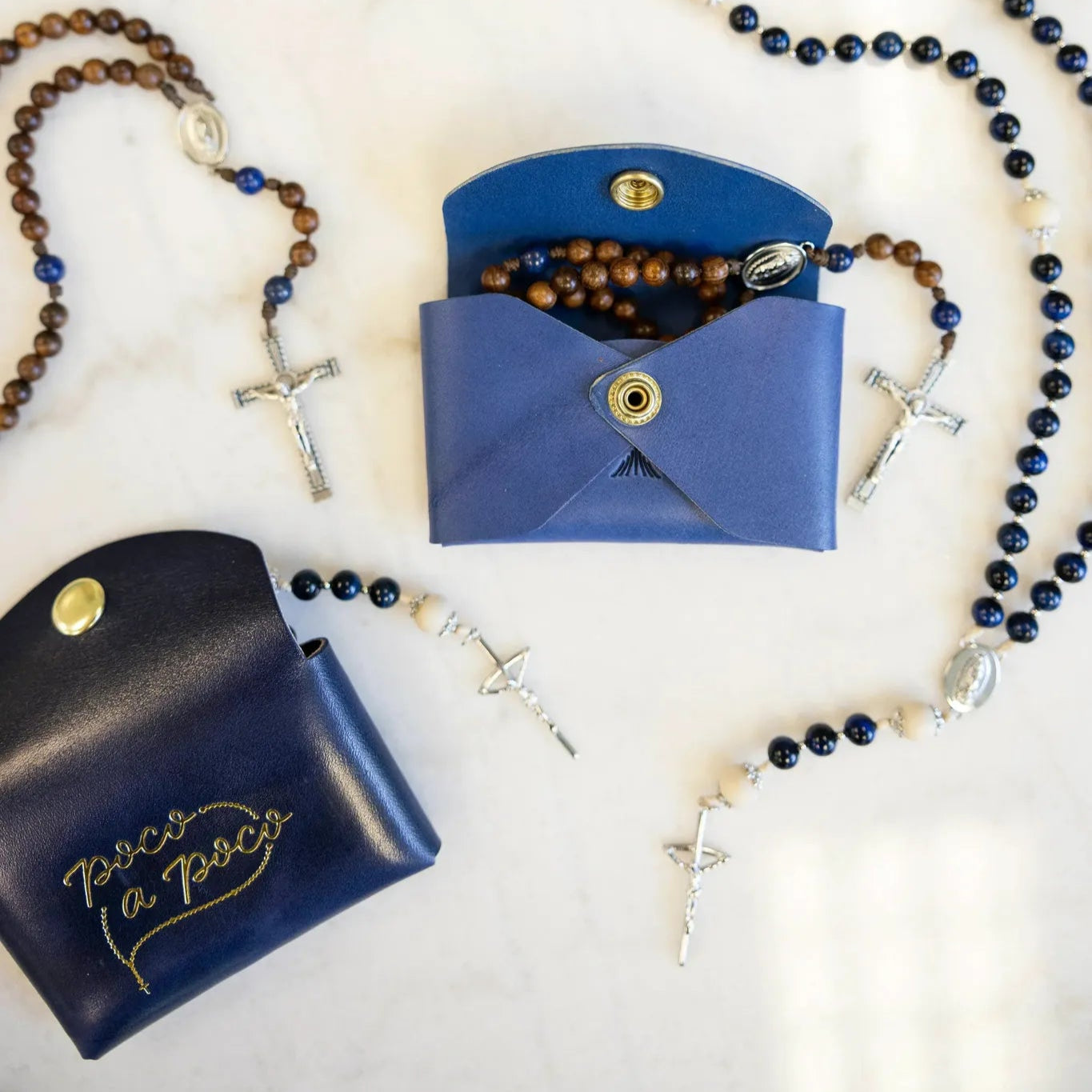 Two blue leather rosary cases with rosary beads on a light background