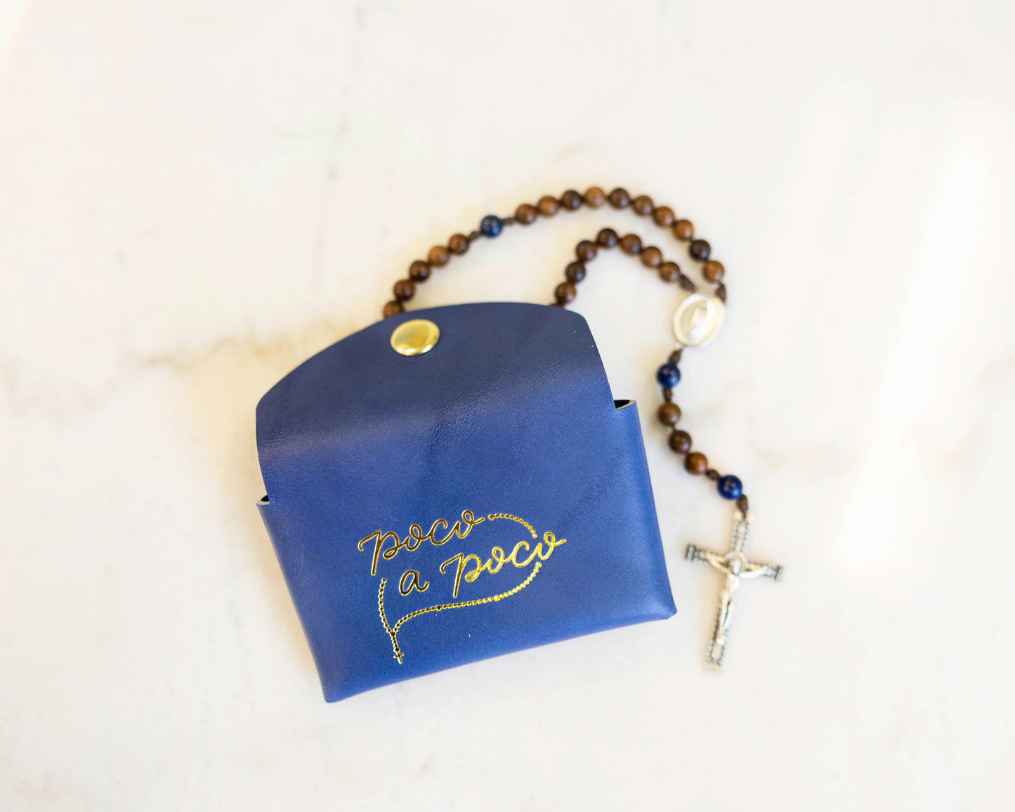 Blue pouch with gold text and a rosary on a white background