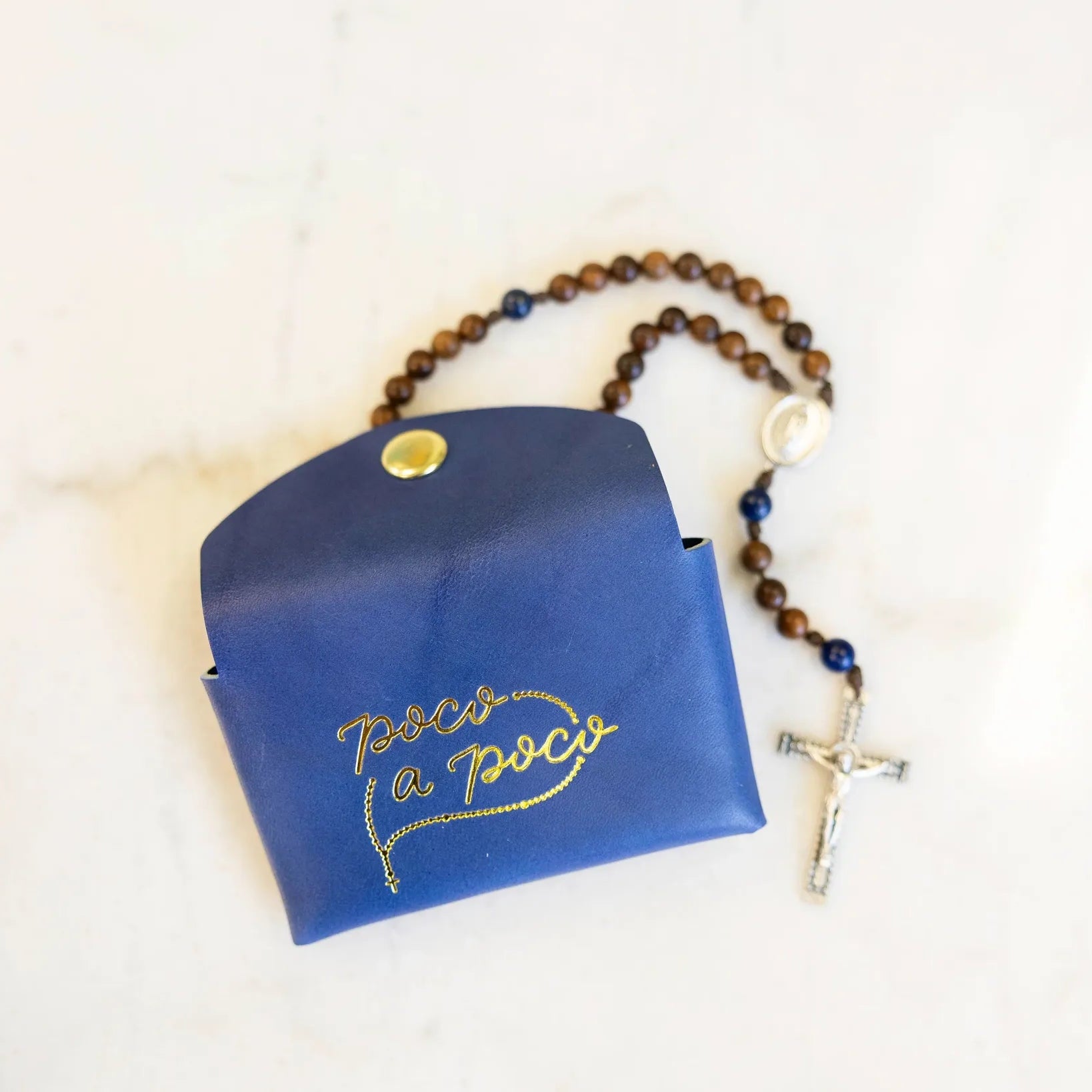 Blue pouch with gold text and a rosary on a white background