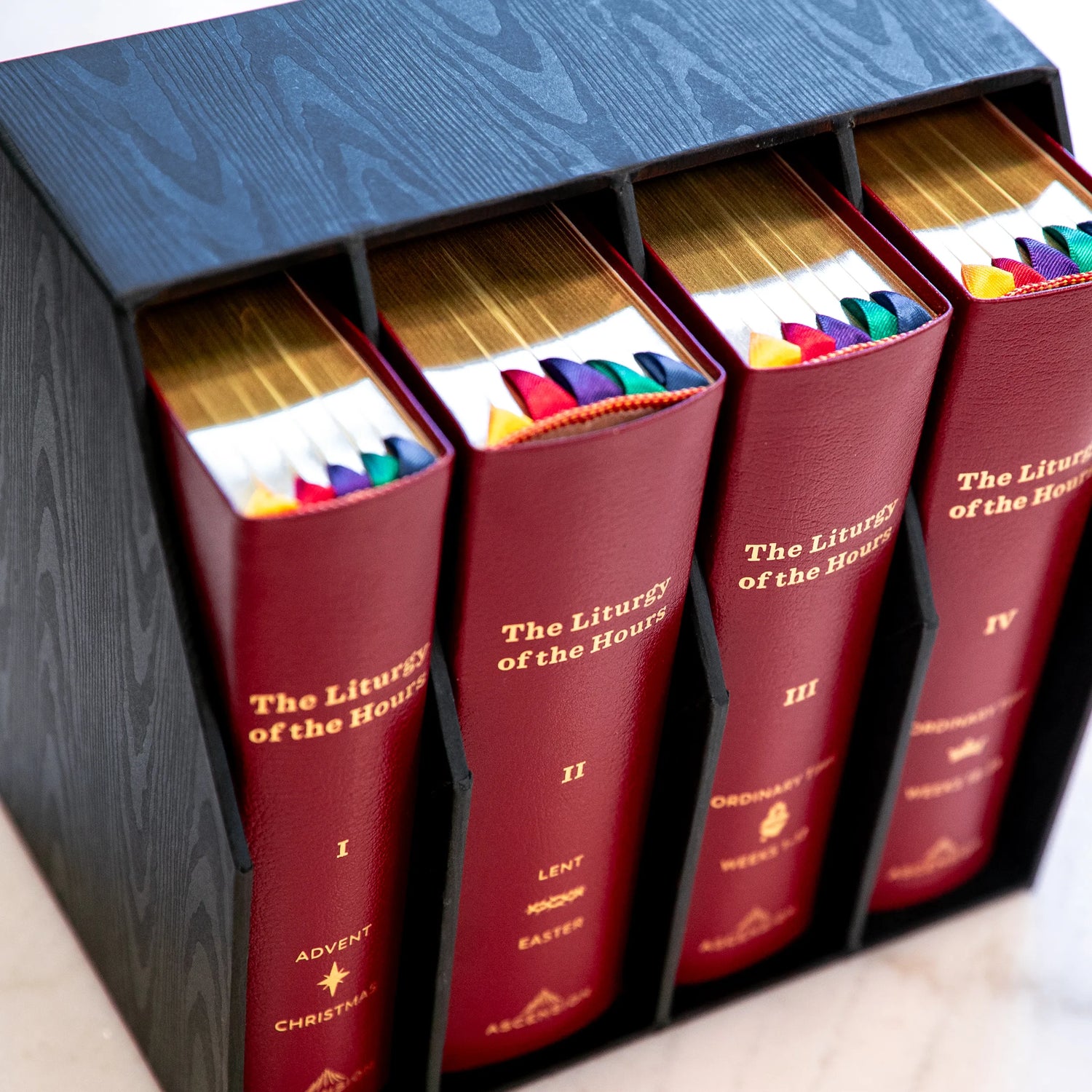 Set of books titled 'The Liturgy of the Hours' with colorful markers inside, arranged in a box.