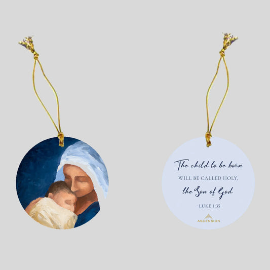 Decorative Christmas ornament with a scene of Mary holding baby Jesus on one side, and biblical text on a white background on the other side.