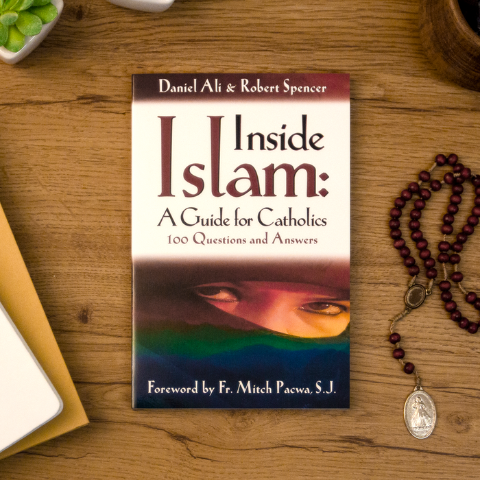 A tabletop lifestyle shot of the catholic book, Inside Islam: A Guide for Catholics by Daniel Ali and Robert Spencer published by Ascension, sitting on a wooden table next to a rosary. The cover features a muslim.