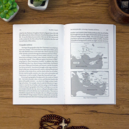 A tabletop lifestyle shot of the catholic book, The Bible Compass: A Catholic's Guide to Navigating the Scriptures by Edward Sri published by Ascension, laying open on a wooden table. 